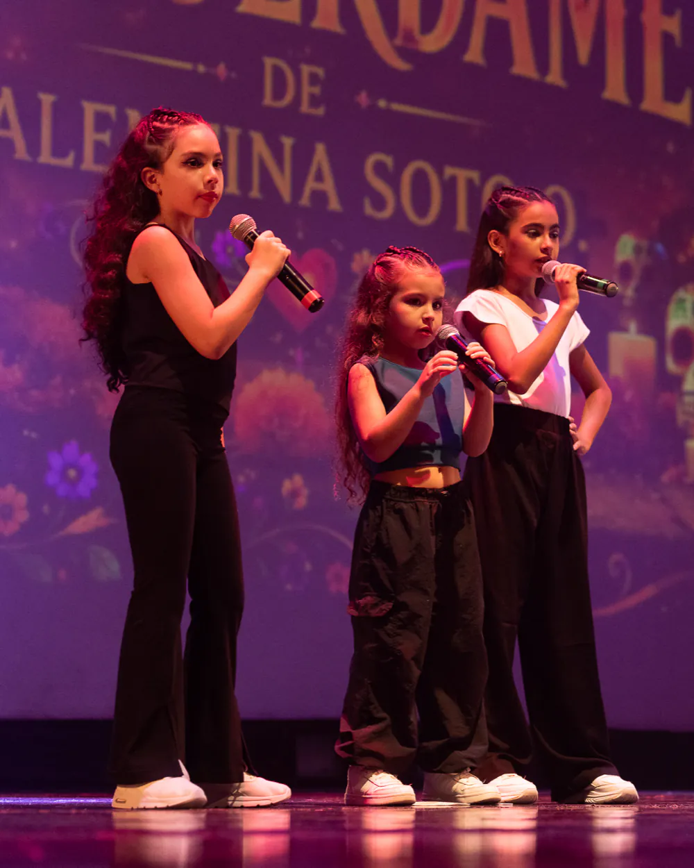 Alumnas de Faith cantando en trío sobre el escenario